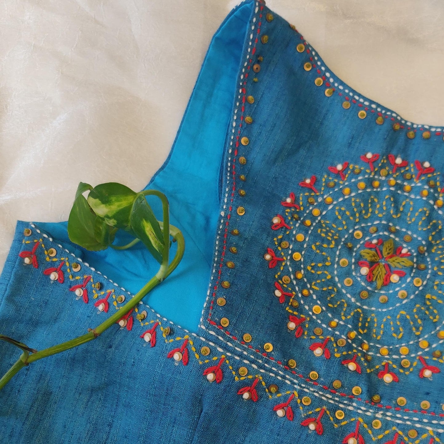 Blue embroidered fabric with intricate patterns on a beige background