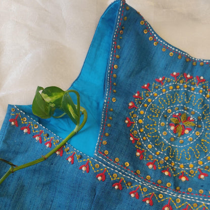 Blue embroidered fabric with intricate patterns on a beige background